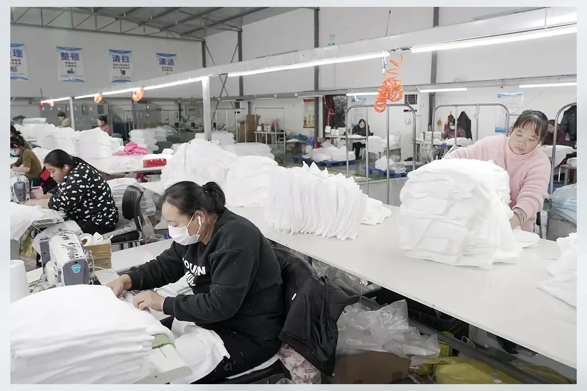 Factory team sewing and inspecting white bath towels before packing