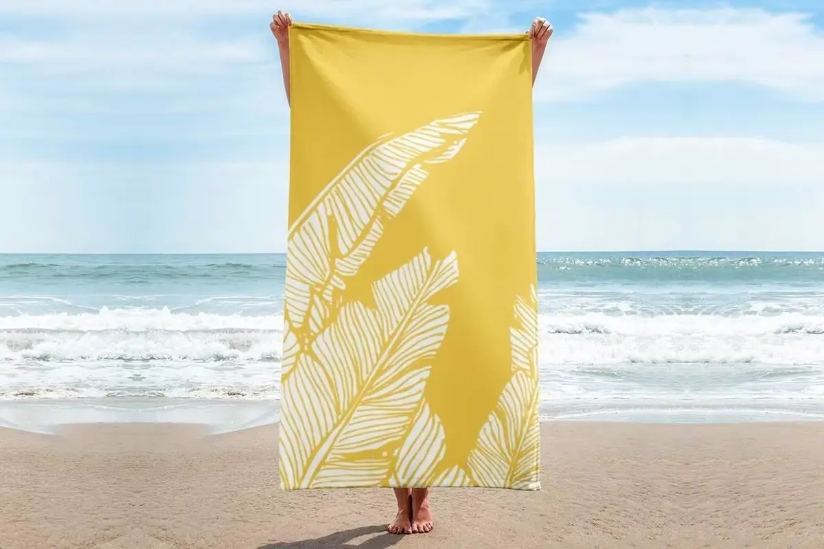 Centered white leaf illustration on a yellow beach towel