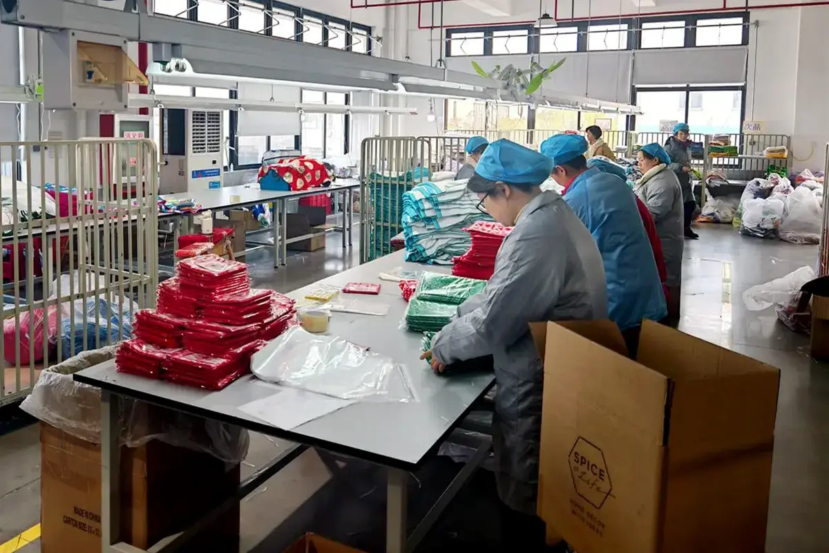 Factory workers checking, folding, and organizing finished towels before packing