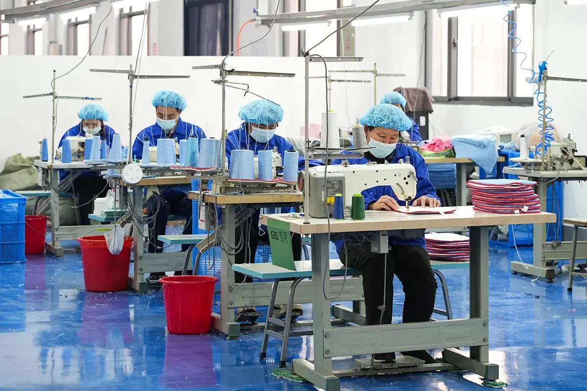 Factory workers sewing and finishing towel products on an organized production line