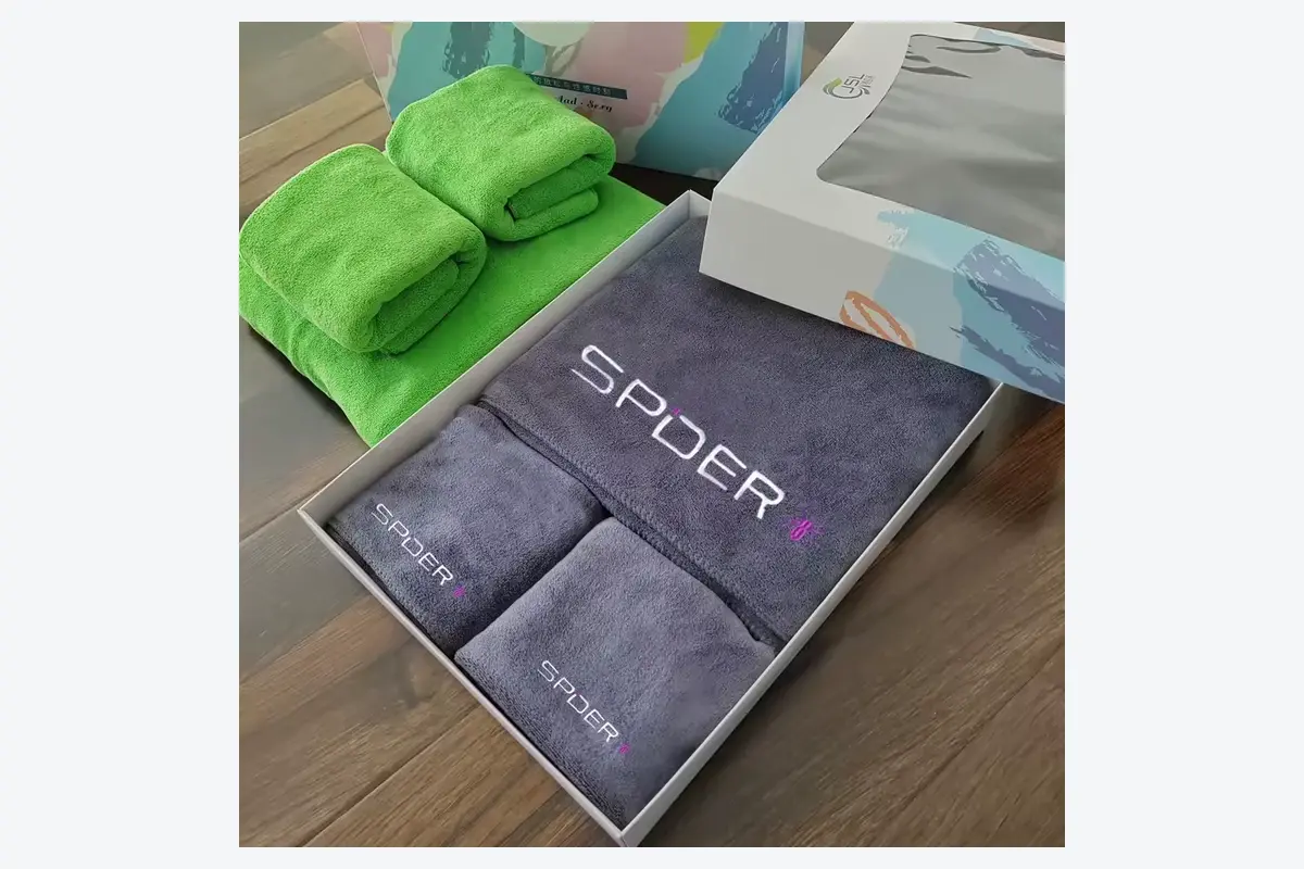 Gray embroidered gym towel set arranged in a branded retail gift box
