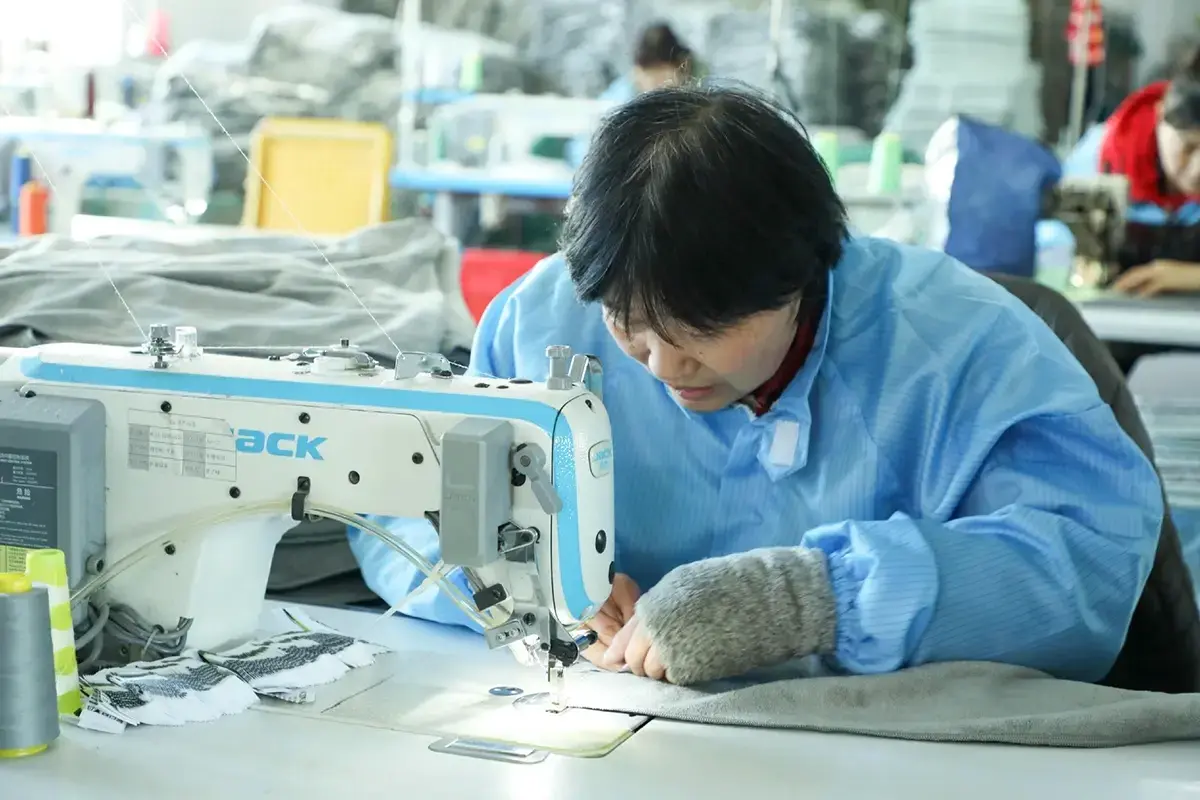 Factory worker stitching and checking a finished hotel towel
