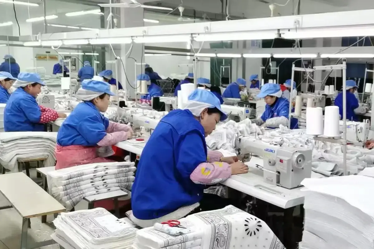 Factory team sewing and inspecting towel edges during bulk production