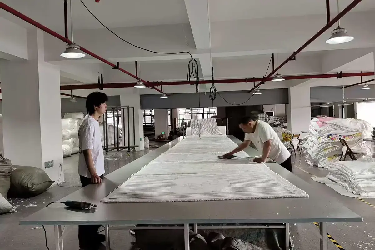 Factory workers inspecting towel fabric across a large quality-control table
