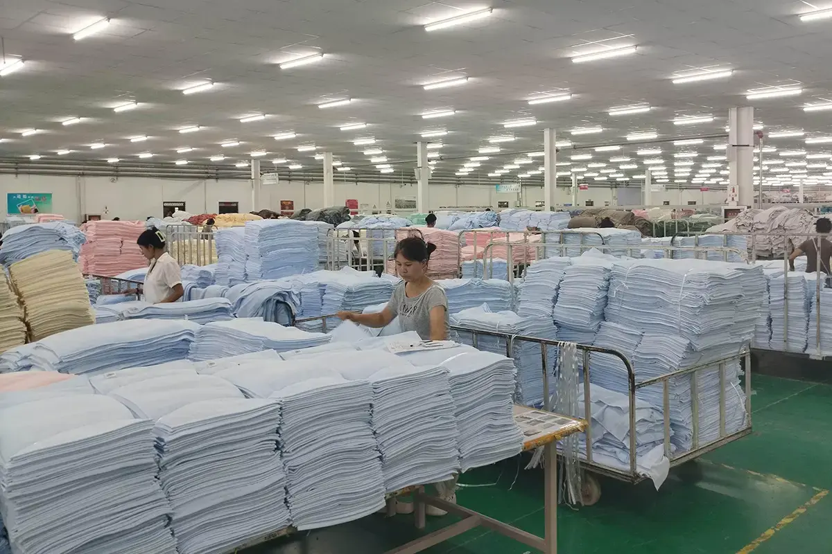 Workers organizing batches of pastel towels on the factory production floor
