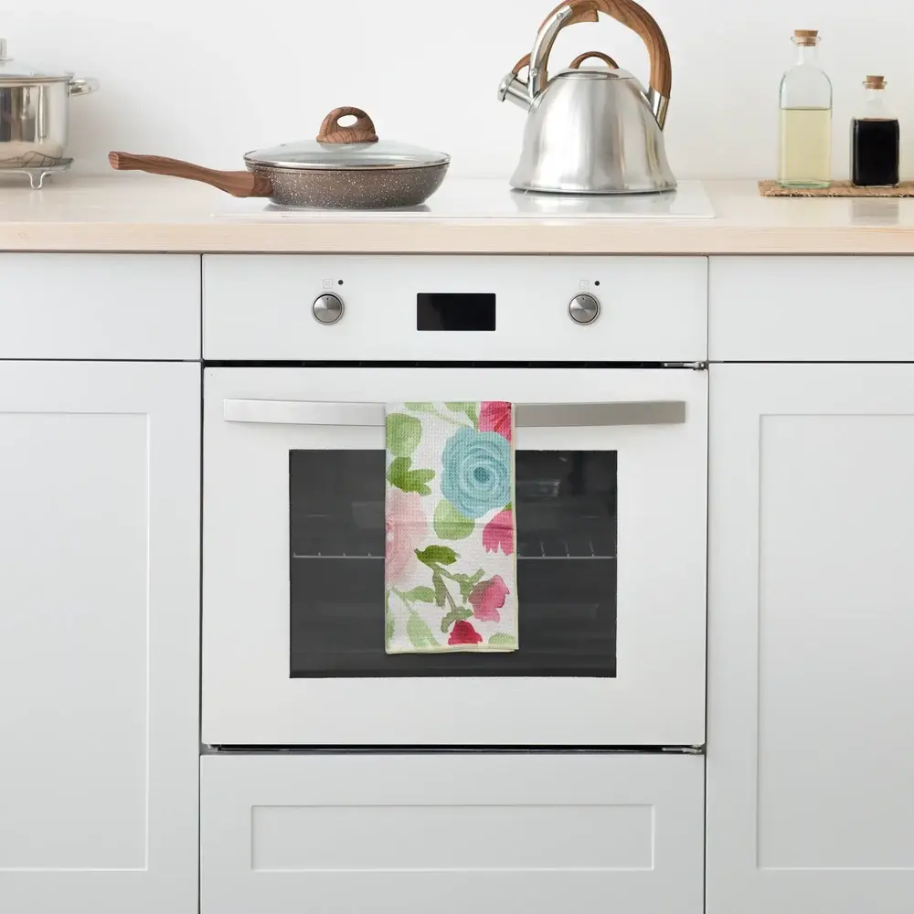 Floral kitchen tea towel hanging from a white oven