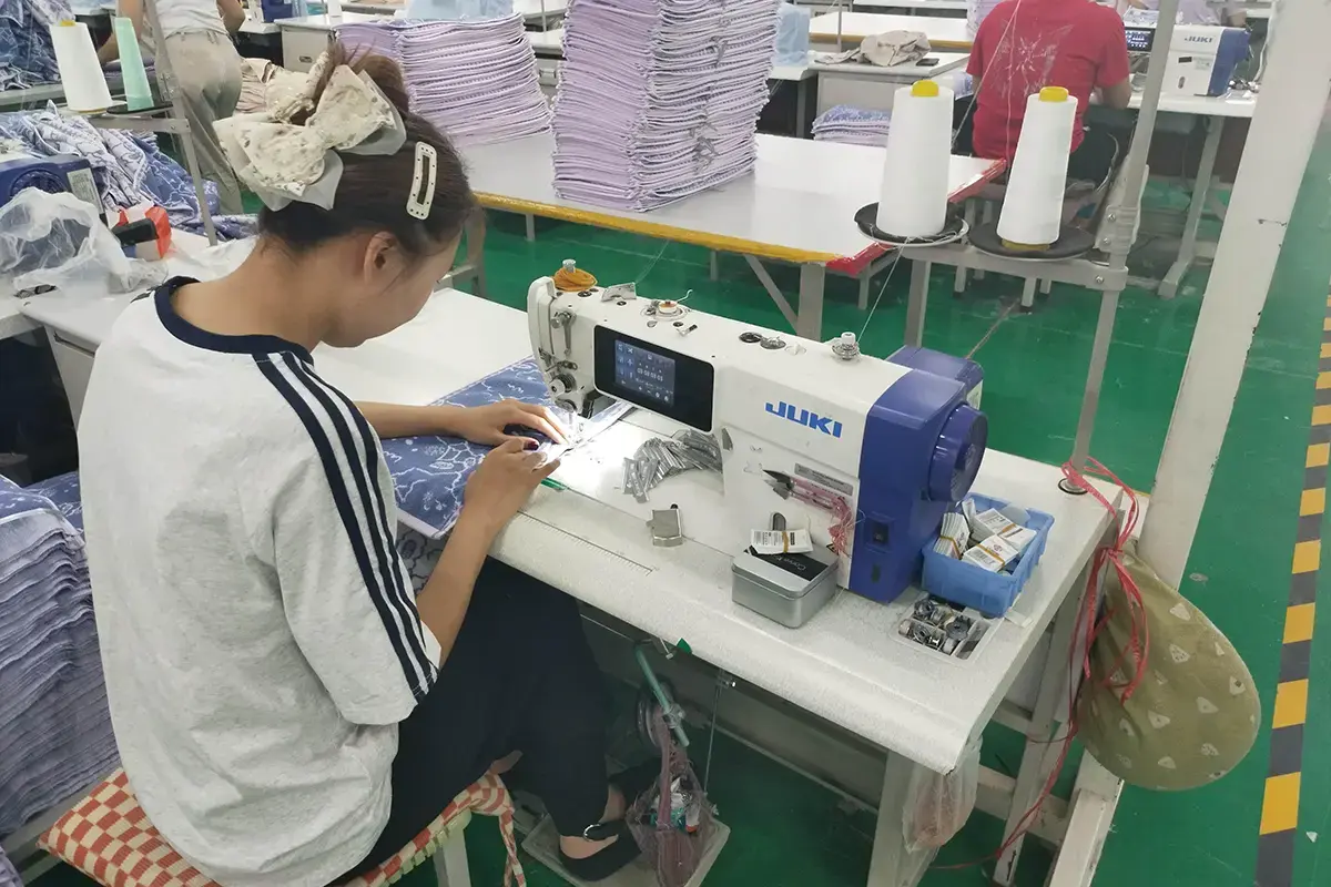 Worker sewing custom labels and finishing details onto towel products