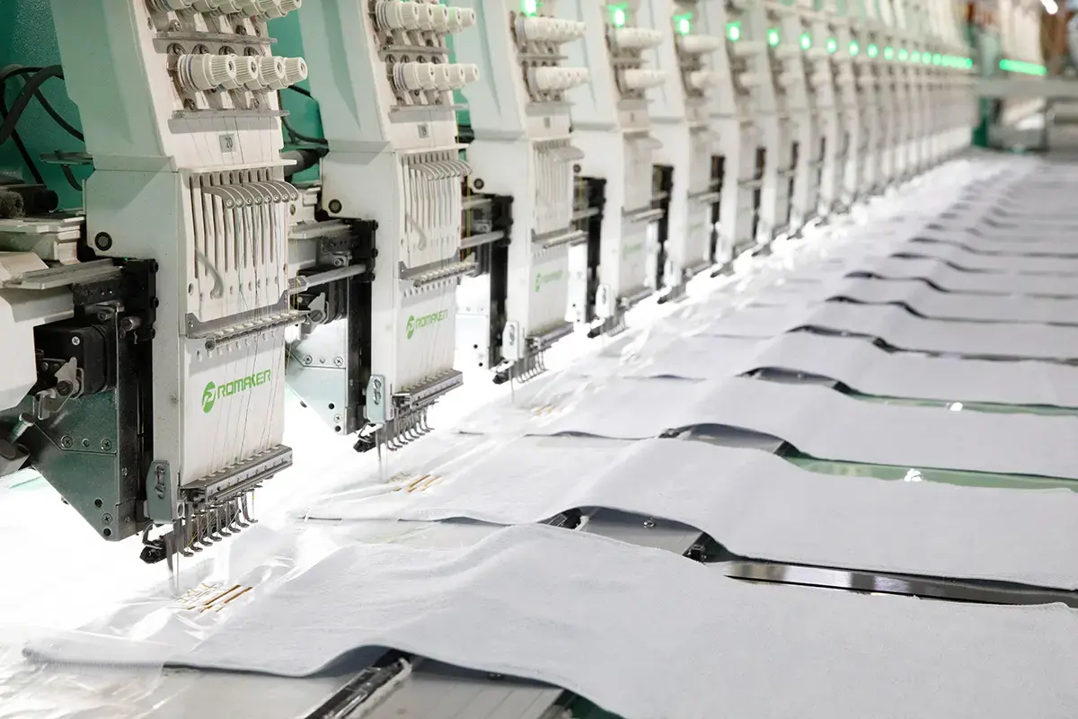 Multi-head embroidery machines producing custom logo designs for towels