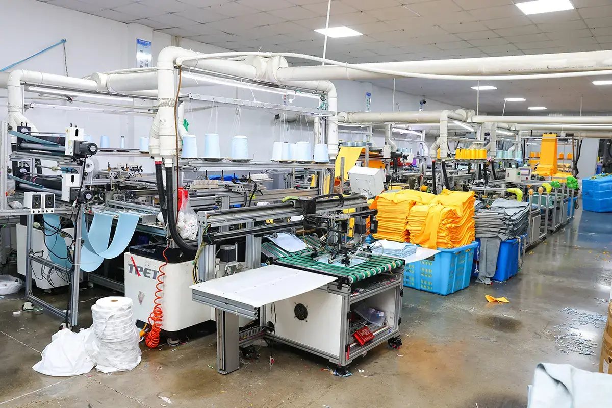 Automated towel production line with finished color batches staged beside the machines
